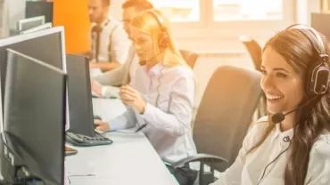 Customer service representatives working on computers with headsets.