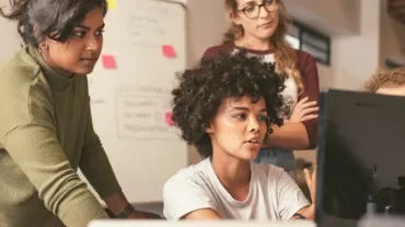 Team collaborating on a computer project in an office.