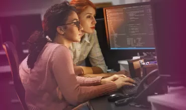 Two people working intently on computer code.